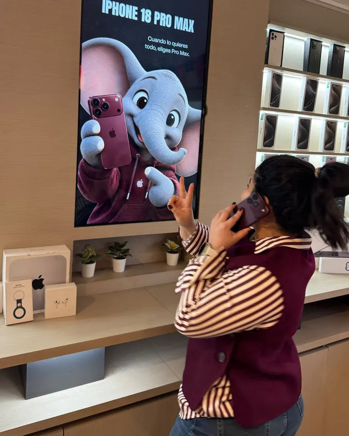 Clienta hablando por su iPhone nuevo frente a la pantalla del iPhone 18 Pro Max